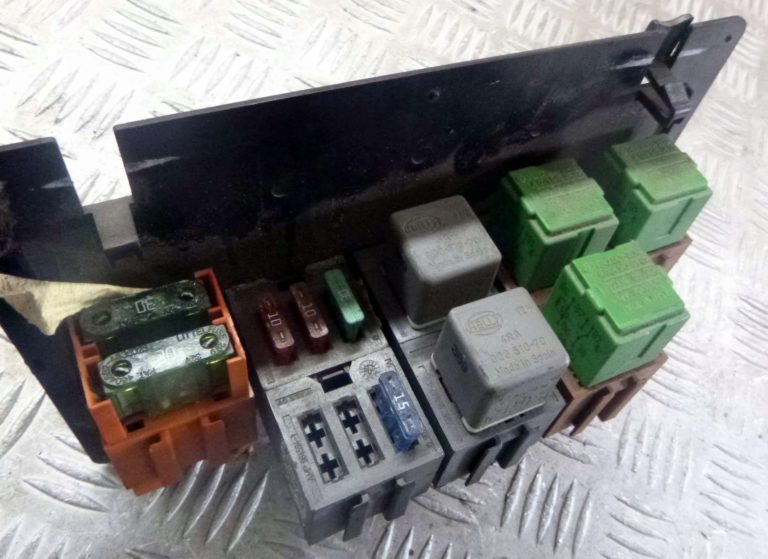Vista ampliada de la caja de fusibles y relés bajo el asiento delantero.